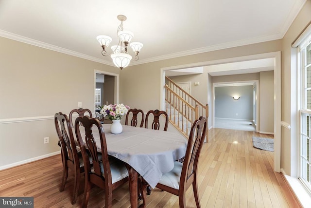 dining space with ornamental molding, light wood-type flooring, a notable chandelier, and baseboards