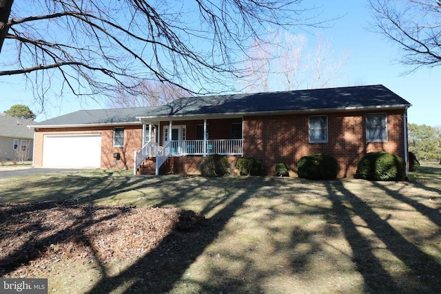 ranch-style home with a porch, brick siding, driveway, and an attached garage