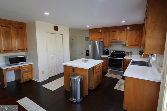 kitchen with under cabinet range hood, a kitchen island, a sink, light countertops, and appliances with stainless steel finishes