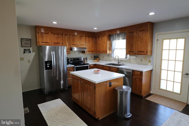 kitchen featuring brown cabinetry, stainless steel appliances, light countertops, under cabinet range hood, and a sink