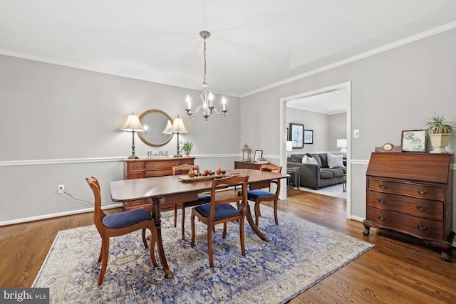 dining area with crown molding, a notable chandelier, wood finished floors, and baseboards