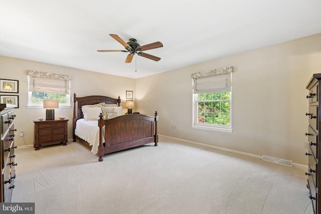 bedroom featuring baseboards, visible vents, multiple windows, and light carpet