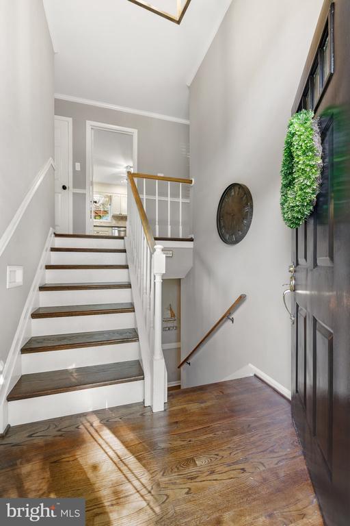 stairs with wood finished floors and crown molding