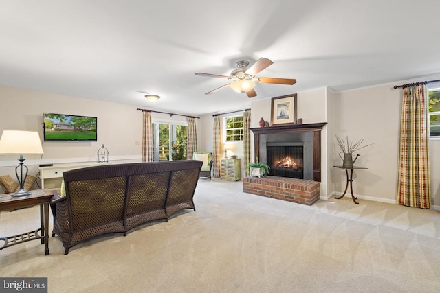 living area featuring ornamental molding, a ceiling fan, carpet flooring, baseboards, and a brick fireplace