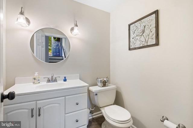 half bath featuring baseboards, toilet, and vanity