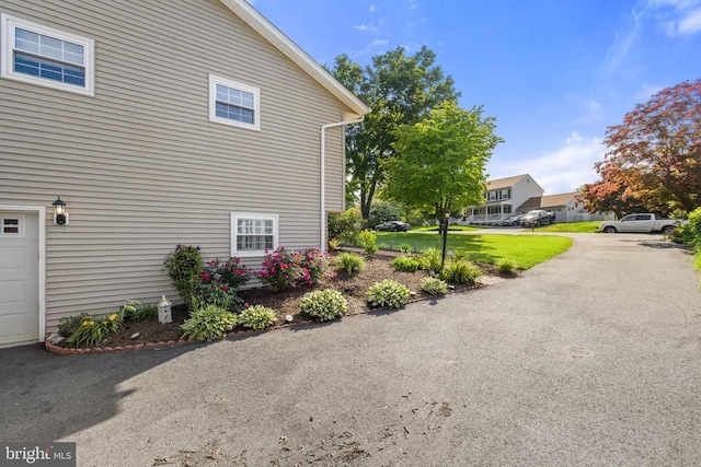 view of side of home featuring a lawn and a garage