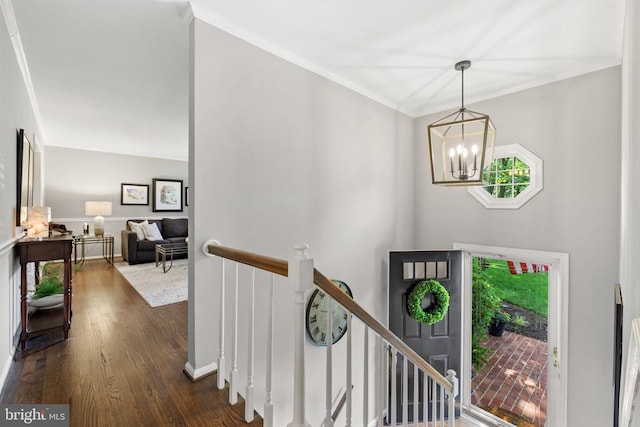 foyer entrance with an inviting chandelier, baseboards, dark wood-type flooring, and ornamental molding