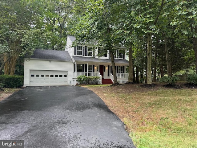 colonial-style house with aphalt driveway, covered porch, and an attached garage