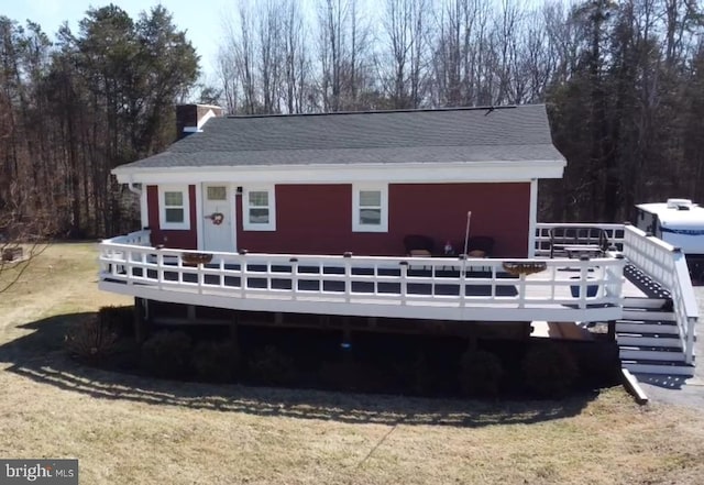 exterior space with a wooden deck, a yard, and a shingled roof