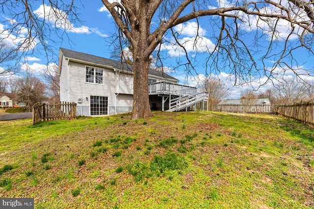 rear view of property featuring stairs, a yard, fence, and a wooden deck