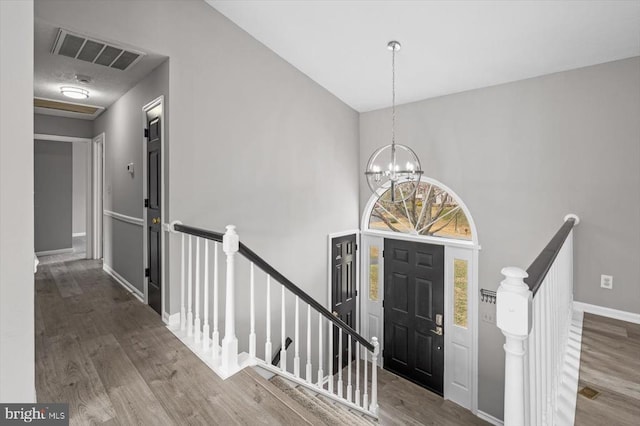 entryway featuring visible vents, baseboards, an inviting chandelier, and wood finished floors