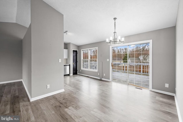 unfurnished dining area with an inviting chandelier, wood finished floors, visible vents, and a textured ceiling