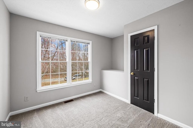 carpeted empty room featuring visible vents and baseboards