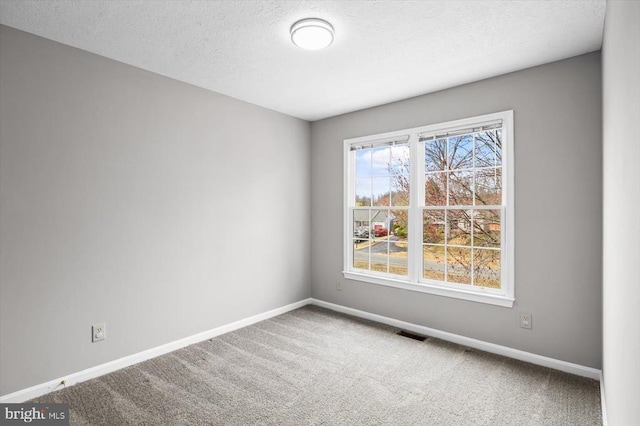 carpeted empty room with visible vents, baseboards, and a textured ceiling