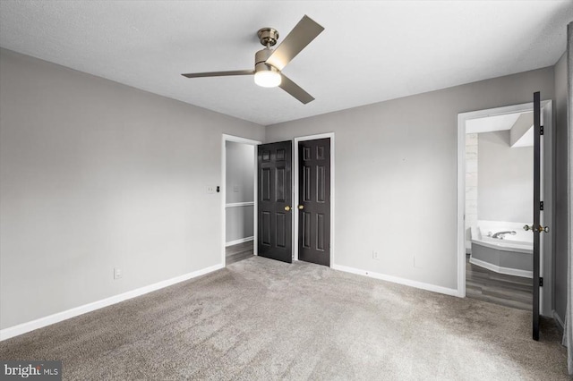 unfurnished bedroom featuring ensuite bathroom, carpet flooring, baseboards, and a closet