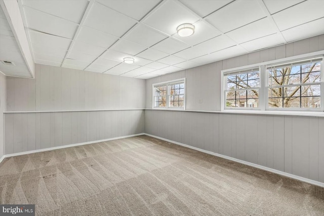 unfurnished room with carpet flooring, baseboards, and a drop ceiling