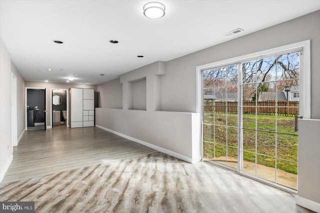 unfurnished room with wood finished floors, visible vents, and baseboards