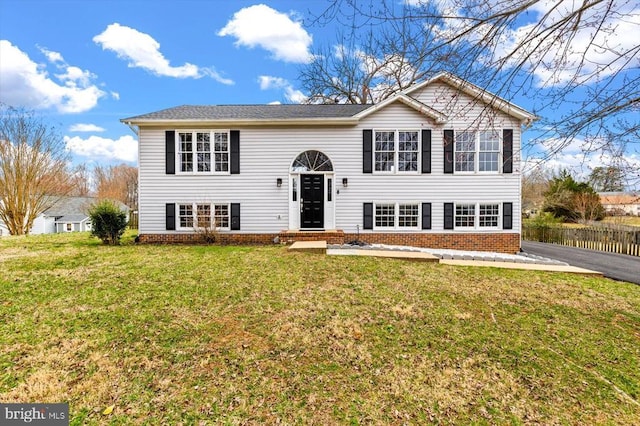 split foyer home with a front lawn and brick siding