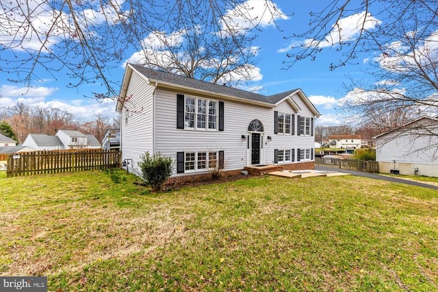 split foyer home with a front lawn and fence