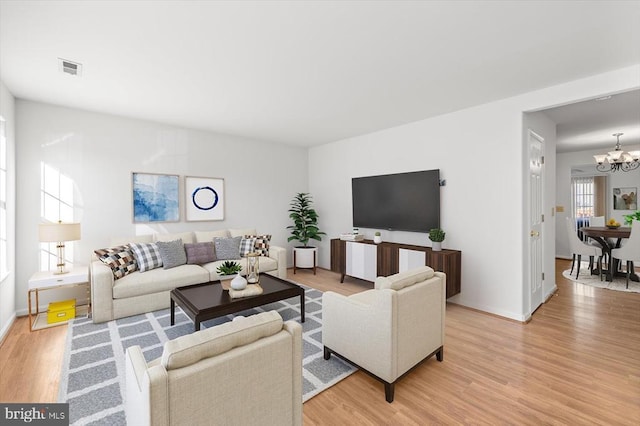 living area with light wood-type flooring, baseboards, visible vents, and a chandelier