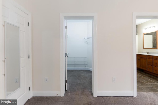 hallway featuring baseboards, carpet floors, and a sink