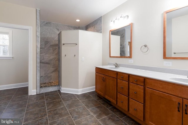 full bath with a sink, a walk in shower, baseboards, and double vanity