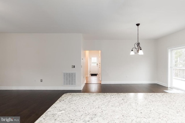 interior space with visible vents, baseboards, a notable chandelier, and dark wood-style flooring