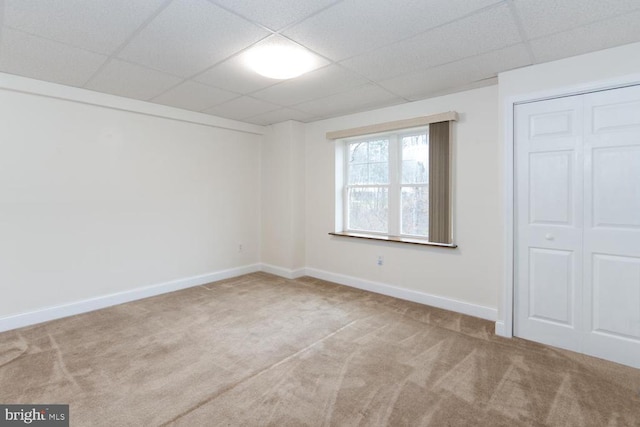 unfurnished bedroom with a drop ceiling, baseboards, and carpet floors