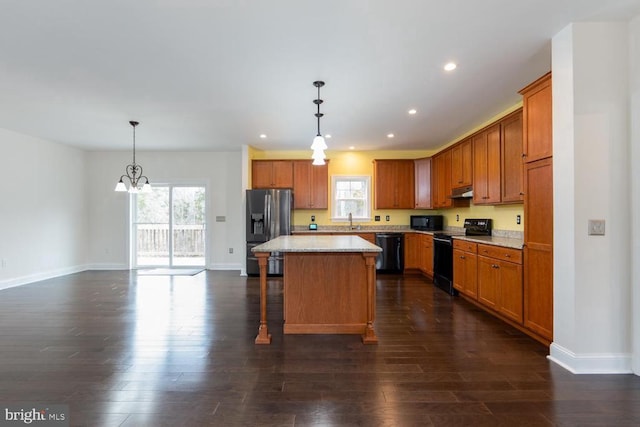 kitchen featuring dark wood finished floors, a notable chandelier, a center island, and black appliances