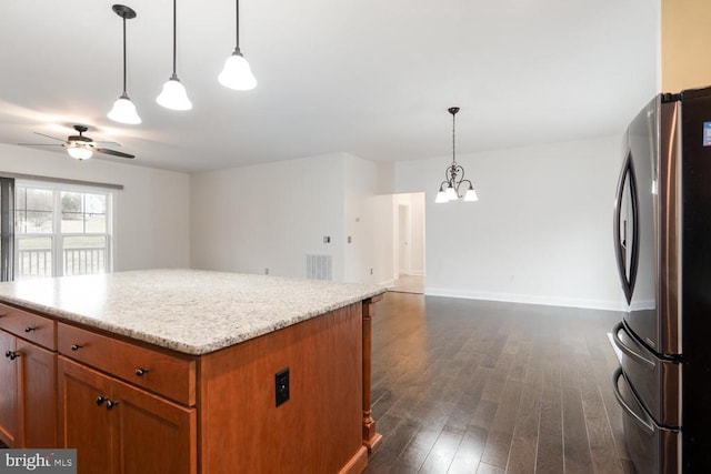 kitchen featuring dark wood-style floors, brown cabinetry, freestanding refrigerator, ceiling fan with notable chandelier, and open floor plan