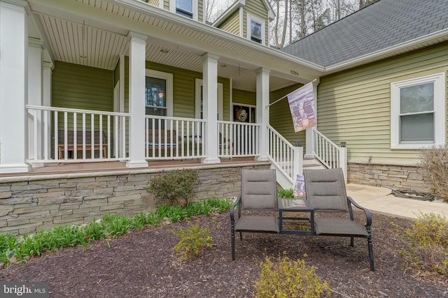 doorway to property with a porch and roof with shingles