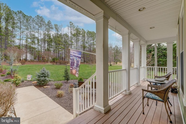 wooden terrace with covered porch and a yard