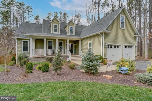 new england style home with a porch, a garage, driveway, and roof with shingles