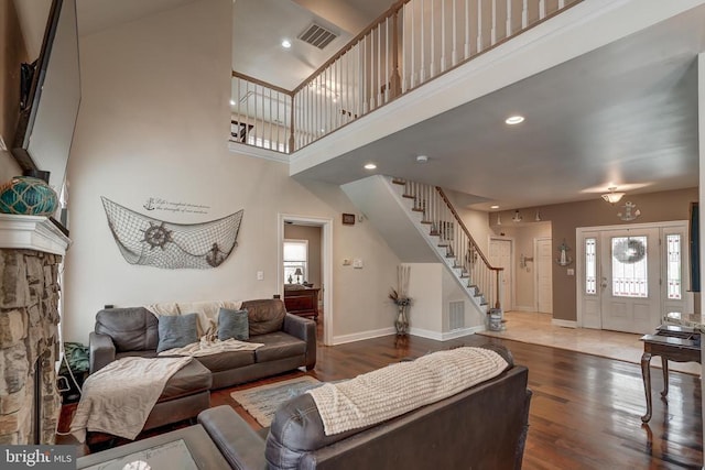 living room with visible vents, wood finished floors, baseboards, a towering ceiling, and stairs