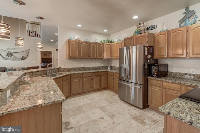 kitchen featuring light stone counters, stainless steel fridge with ice dispenser, recessed lighting, a sink, and hanging light fixtures