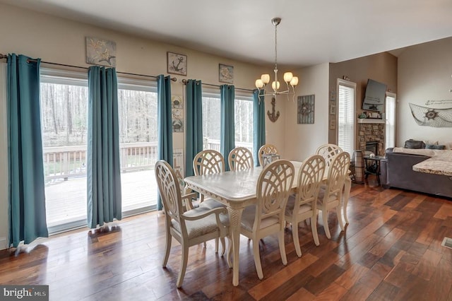 dining room featuring a chandelier, a fireplace, and dark wood-type flooring