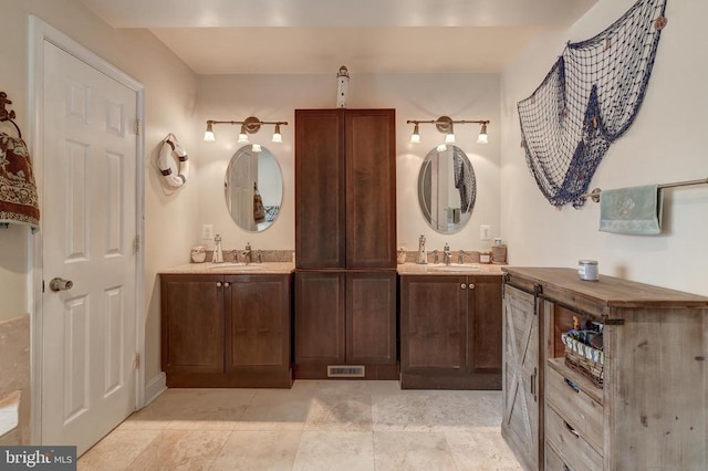 bathroom with double vanity, visible vents, and a sink