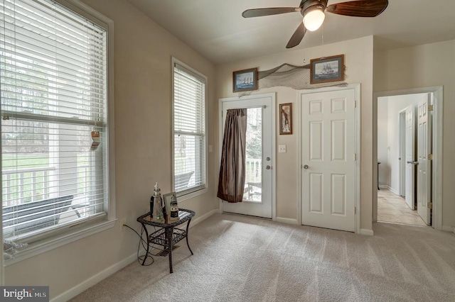 carpeted entrance foyer with baseboards and ceiling fan