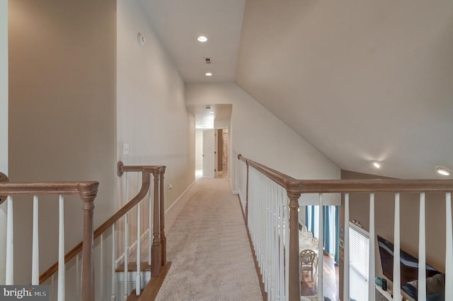 hallway featuring visible vents, lofted ceiling, recessed lighting, carpet flooring, and an upstairs landing