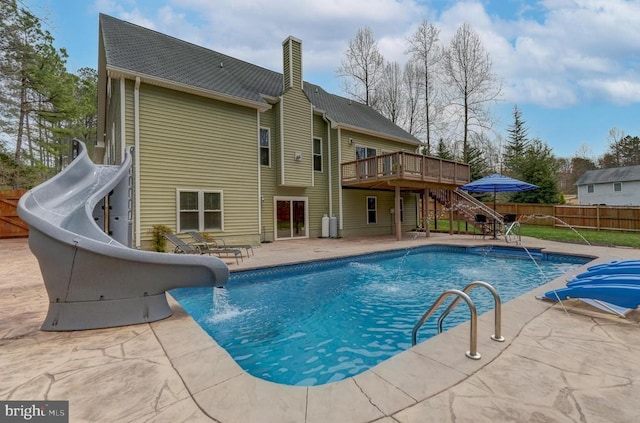 view of swimming pool featuring a water slide, fence, stairway, a deck, and a patio