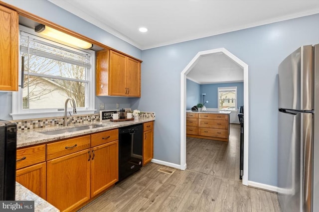 kitchen featuring a sink, plenty of natural light, black dishwasher, and freestanding refrigerator