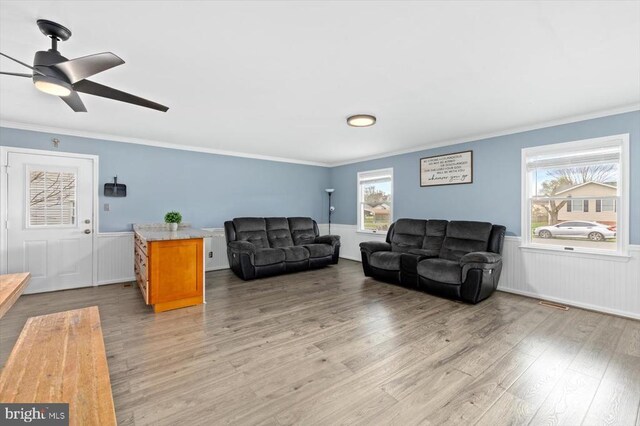 living area featuring a healthy amount of sunlight, light wood finished floors, and wainscoting