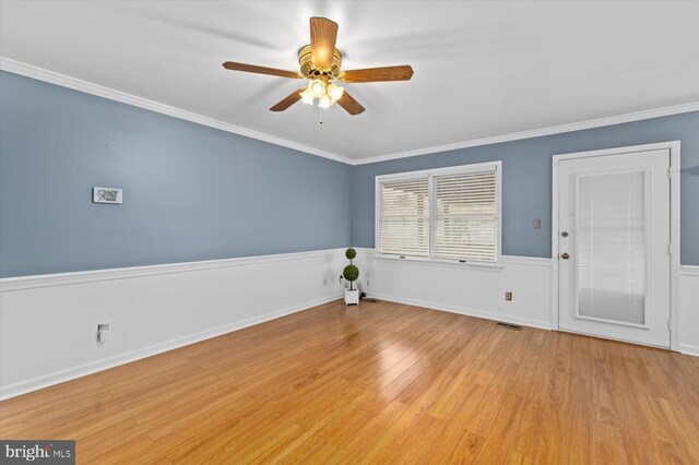 unfurnished room with visible vents, crown molding, baseboards, wood finished floors, and a ceiling fan