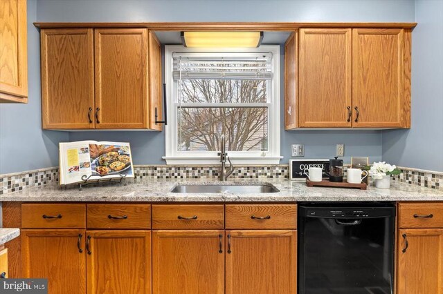 kitchen with black dishwasher, a sink, and brown cabinetry