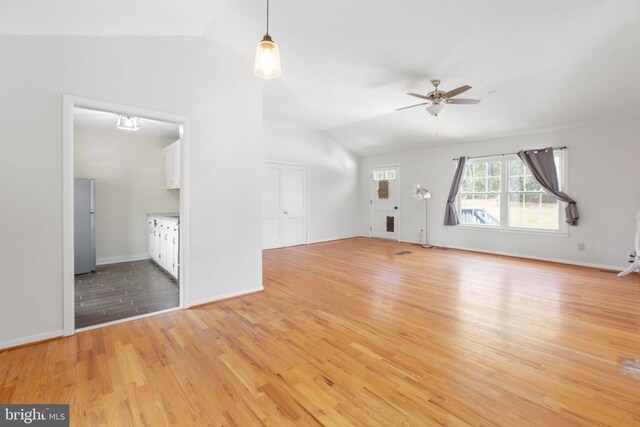 unfurnished living room featuring baseboards, lofted ceiling, a ceiling fan, and light wood finished floors