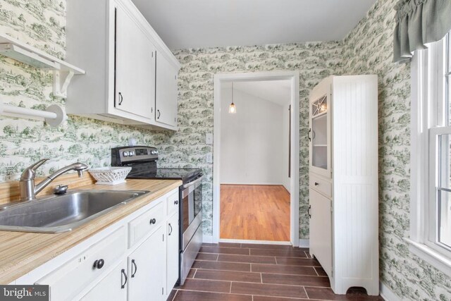 kitchen with electric stove, wallpapered walls, light countertops, and a sink