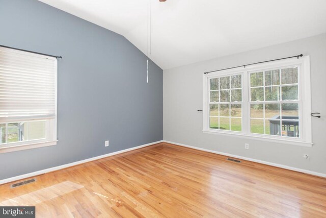 empty room featuring a healthy amount of sunlight, lofted ceiling, and visible vents