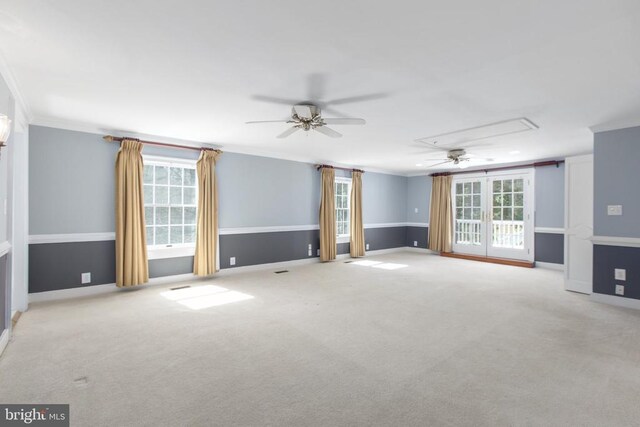 empty room featuring carpet, a ceiling fan, crown molding, and attic access