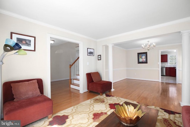 living room featuring wood finished floors, crown molding, baseboards, and decorative columns