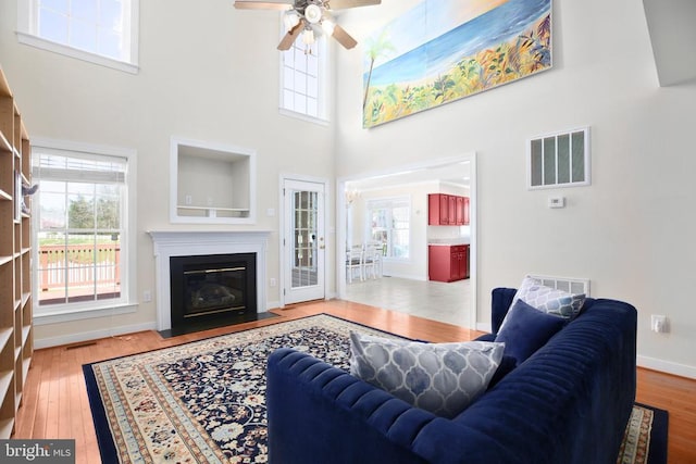living room featuring a wealth of natural light, visible vents, ceiling fan, and hardwood / wood-style floors